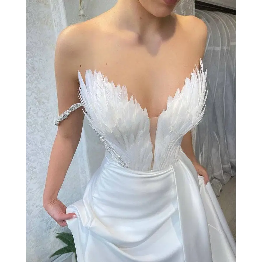 White satin gown with feathered bodice in off the shoulder design and fitted silhouette sweeping the floor