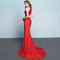 A striking red mermaid evening gown with a fitted bodice and flowing train for formal skirt length events