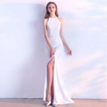 A white satin halter neck evening dress with a fitted silhouette and high slit skirt length for formal events