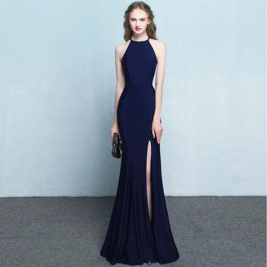 A sleek navy blue halter neck evening dress with a high slit and flowing silhouette showcasing skirt length