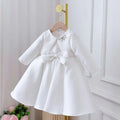 White satin long sleeve baby dress with matching waist bow and silver rhinestone bow in white classic style
