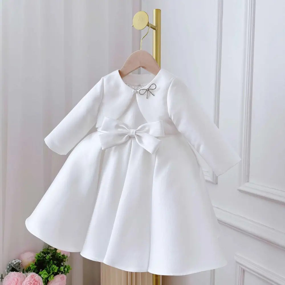 White satin long sleeve baby dress with matching waist bow and silver rhinestone bow in white classic style