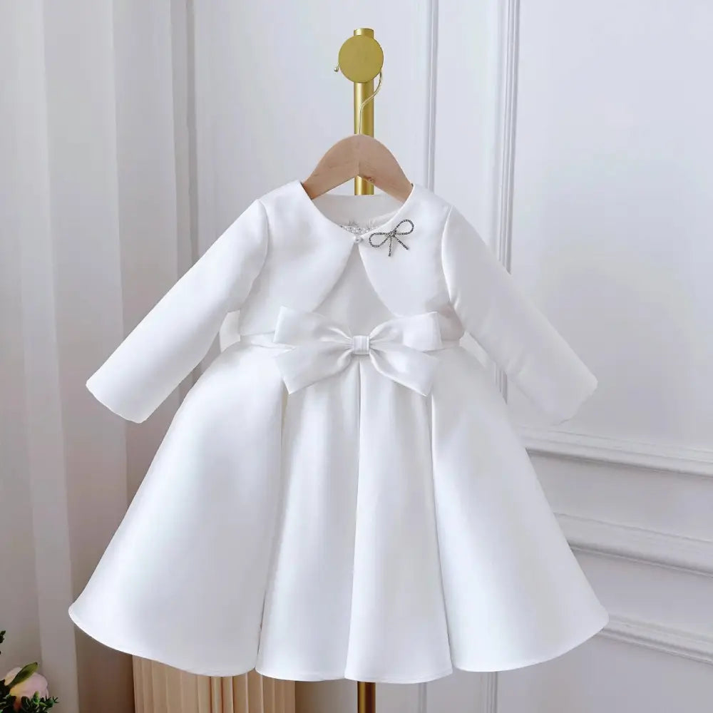 White satin long sleeve baby dress white classic style with large waist bow and silver embellished bow neckline