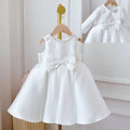White satin sleeveless toddler dress with beaded neckline and large bow in elegant white classic style baby dress white