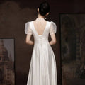 Back view of a white satin engagement wedding dress with sheer puff sleeves and a lace-up back detail