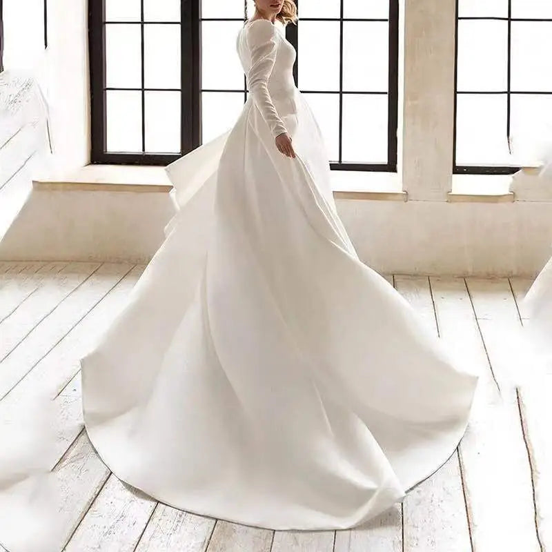 A flowing white satin wedding gown with long sleeves, high neckline, and a long skirt perfect for formal occasions