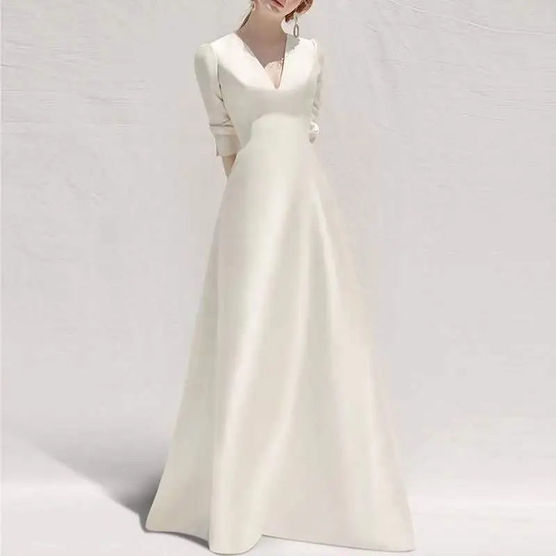 A white satin wedding dress with long skirt features a satin v neck, long sleeves, and a silver buckle belt