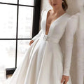 White satin wedding dress with satin v neck, puffed shoulders, fitted waist, matching belt, and long skirt