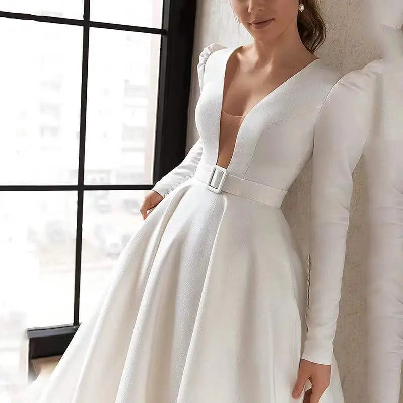 White satin wedding dress with satin v neck, puffed shoulders, fitted waist, matching belt, and long skirt