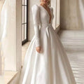 White satin wedding dress with long skirt, satin v neck, long puff sleeves, and silver buckle belt at fitted waist