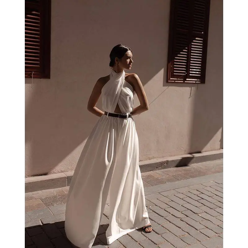 A flowing white sexy sleeveless halter backless jumpsuit with draped neckline and black belt at the waist
