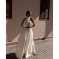 A flowing white sexy sleeveless halter backless jumpsuit with a draped neckline and black belt at the waist