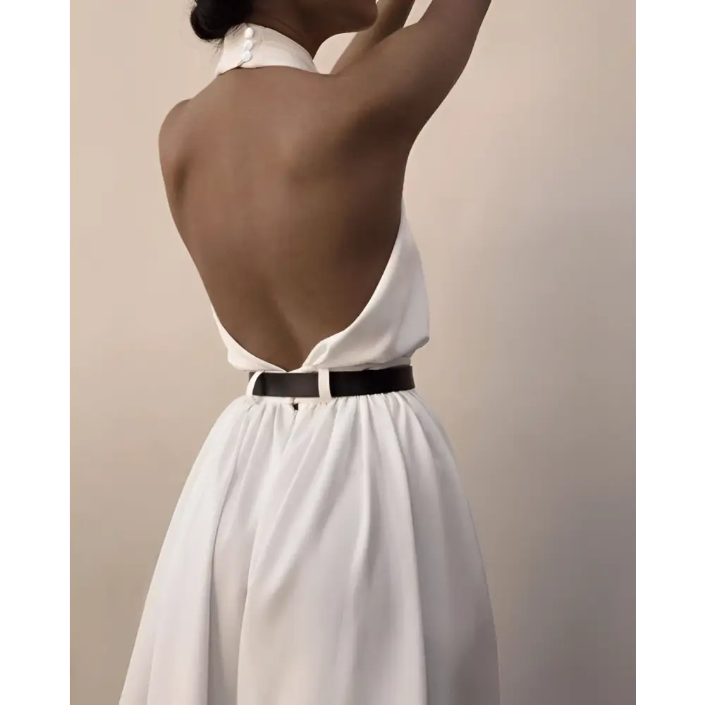White sexy sleeveless halter backless jumpsuit featuring a high collar and black belt viewed from the back side