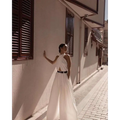 A flowing white sexy sleeveless halter backless jumpsuit with a cutout back and black belt detail