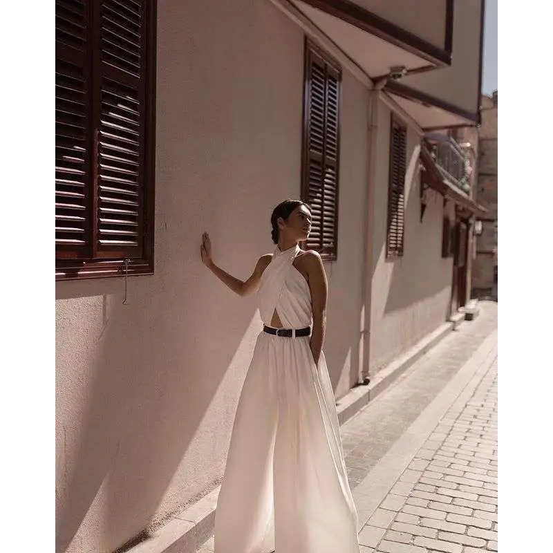 A flowing white sexy sleeveless halter backless jumpsuit with a cutout back and black belt detail