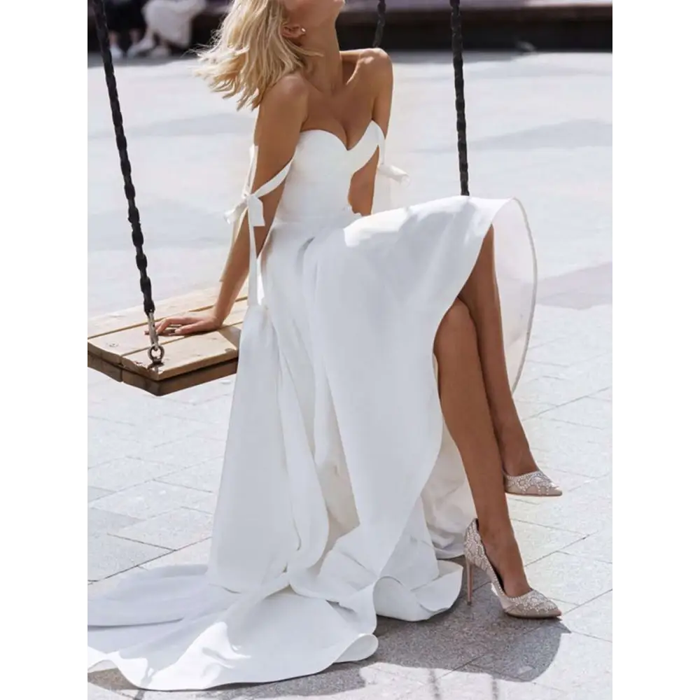 White strapless flowing wedding gown with delicate shoulder ties and a sexy sling high slit for formal occasions