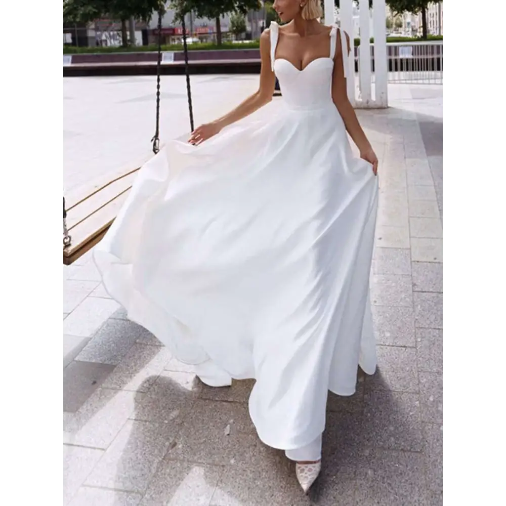 A flowing white satin wedding gown with a sweetheart neckline thin shoulder straps and a sexy sling high slit design