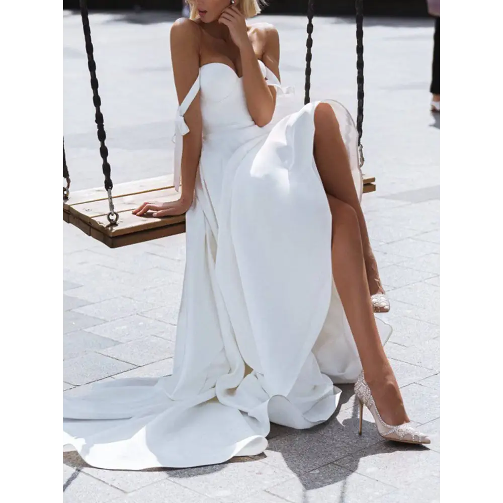 White satin strapless wedding gown with high slit and delicate bow details featuring a sexy sling design