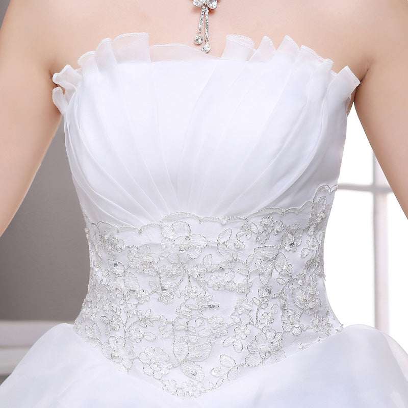 A white strapless wedding dress with a ruffled neckline and intricate silver lace detailing on the bodice ideal for the bridal party including the flower girl.