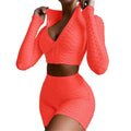 Vibrant coral two-piece athletic set with textured, ribbed fabric and a zip-front top paired with high-waisted shorts