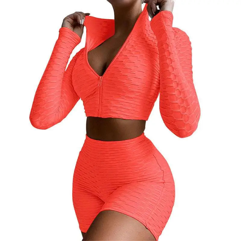 Vibrant coral two-piece athletic set with textured, ribbed fabric and a zip-front top paired with high-waisted shorts