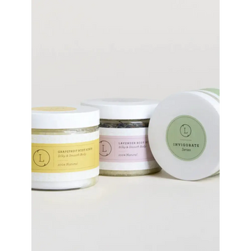 Three glass jars of wholesale natural body scrub set with white lids and yellow pink green minimalist labels display natural ingredients