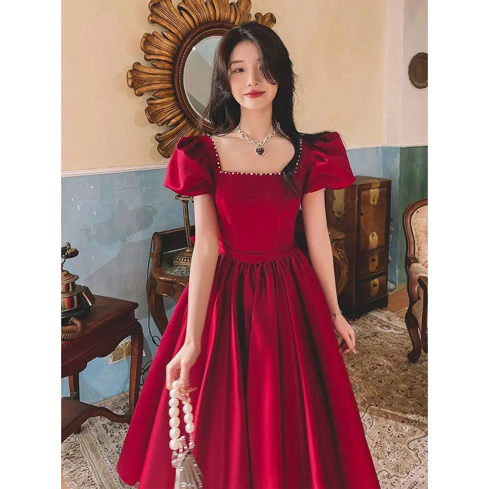 A wine red satin engagement dress with puffed short sleeves and a square neckline with beaded detailing