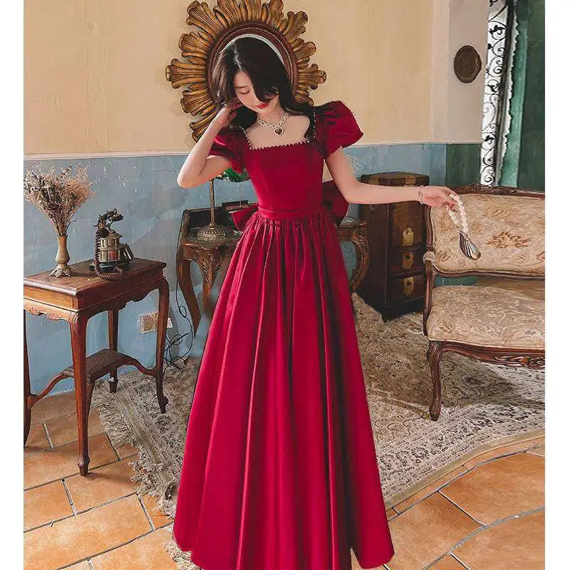 A rich wine red satin engagement dress with square neckline, puffed short sleeves, and fitted waist bow