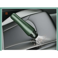 A sleek dark green wireless vacuum cleaner with transparent dust collection suctioning debris from a car seat