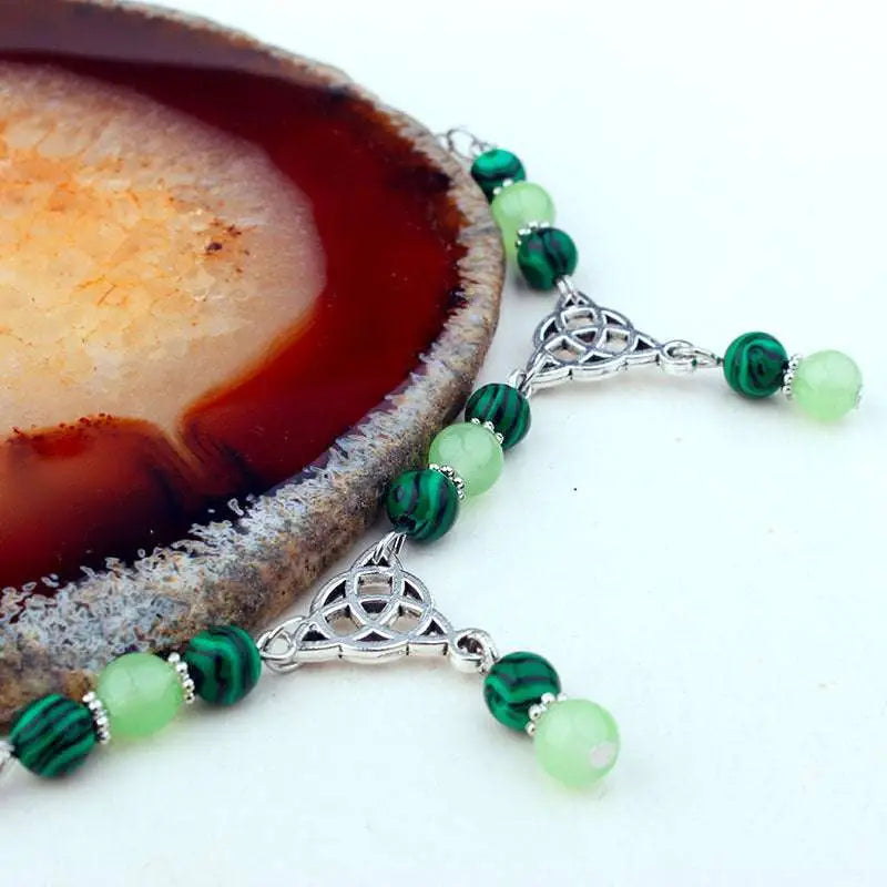 A delicate witchcraft irish knot pagan headpiece with dark green malachite, light green jade beads, and silver celtic charms