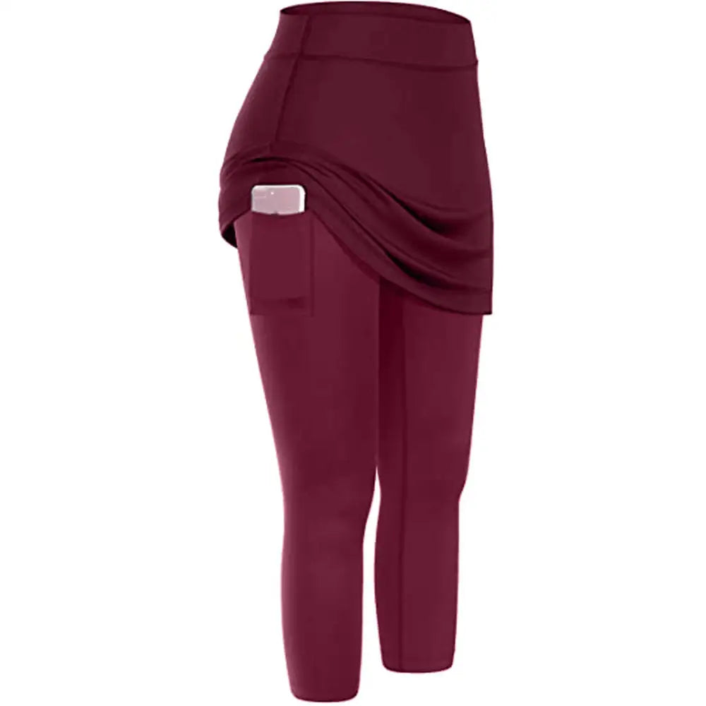 Women tennis skirted leggings in maroon with a high-waisted design and skirted leggings pockets holding a smartphone