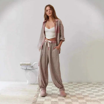 A woman wears a pink muted plaid dressing gown plaid shirt outfit with rolled sleeves and loose fit in beige tones