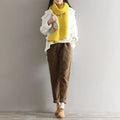 Women’s plus size dark blue corduroy casual trousers paired with a vibrant yellow ribbed knitted scarf worn loosely around the neck