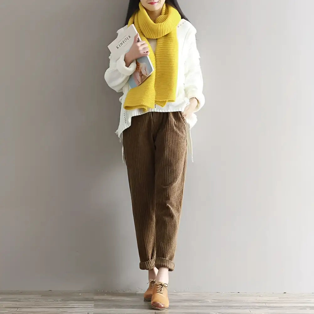Women’s plus size dark blue corduroy casual trousers paired with a vibrant yellow ribbed knitted scarf worn loosely around the neck