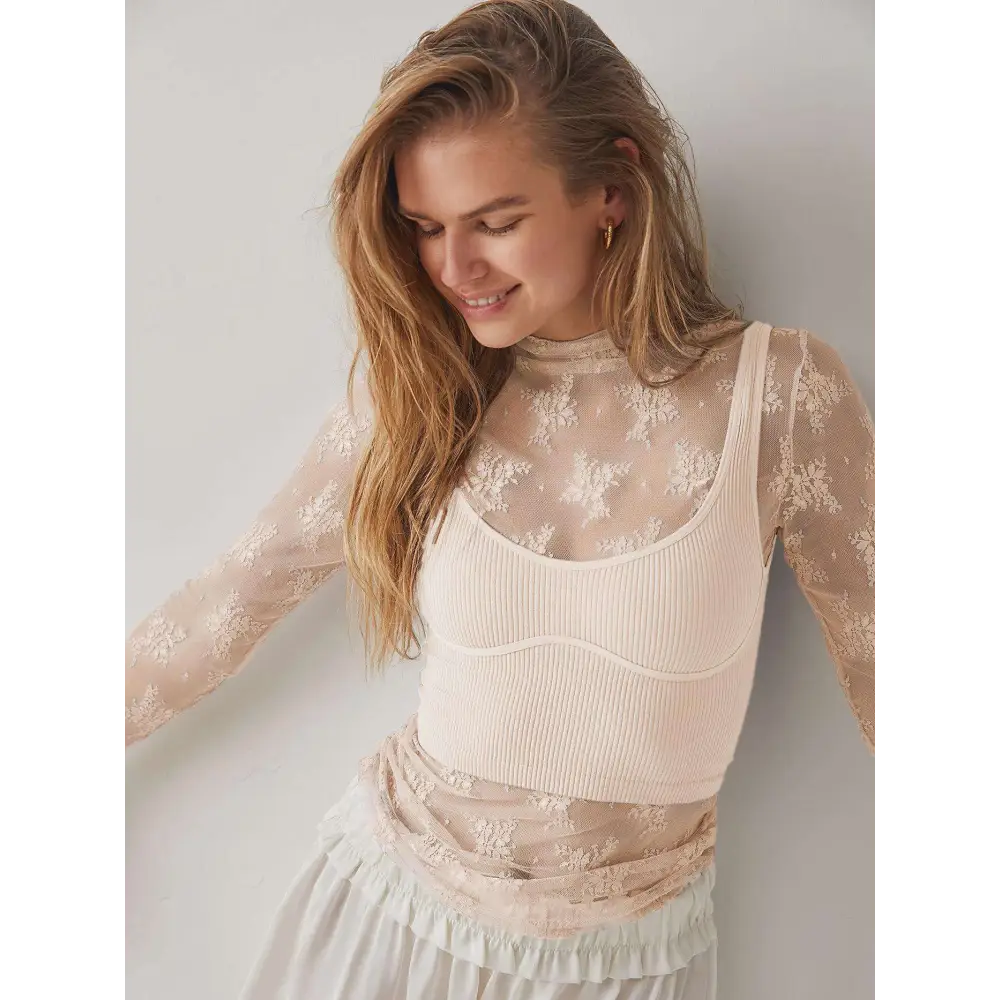 A delicate cream-colored long-sleeved women’s see-through lace floral mesh top with ribbed bodice and high neckline