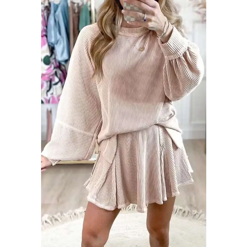A soft blush pink women’s solid colour ribbed knit casual suit with long sleeve top and flared skirt tied at the waist