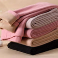 Stack of women’s warm cashmere fleece lined thermal leggings in pastel pink beige and black with rolled cuffs