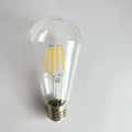 Clear glass edison glass bulb with four yellow led filaments and metallic base for wood pendant lights in living room