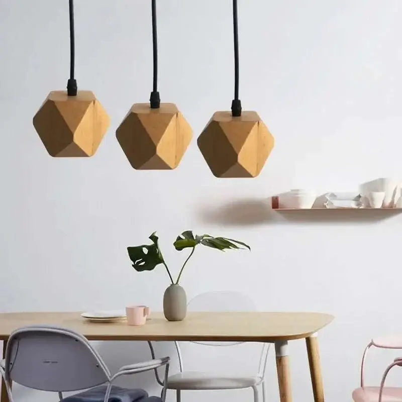 Three geometric wood pendant lights with a warm natural finish and edison glass bulbs hang above a living room table