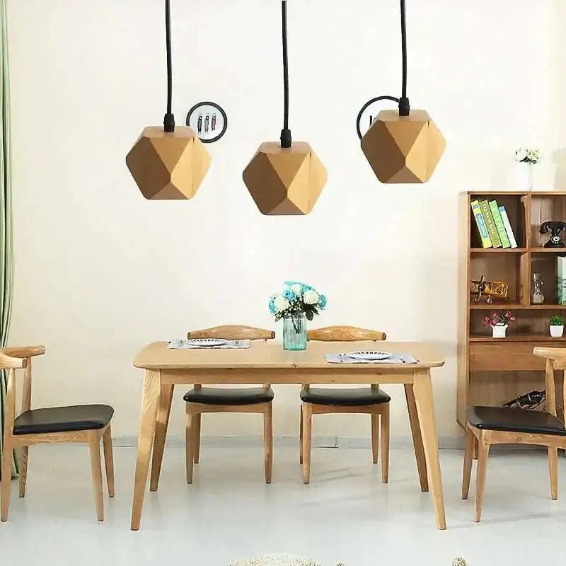 Three geometric wood pendant lights with edison glass bulbs and a warm natural finish hang above a dining table