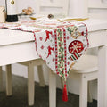 Woven christmas table runner in red green and white with reindeer ornaments holly and matching tassels