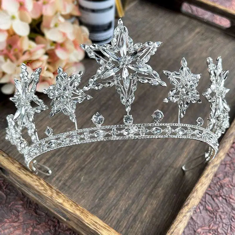 A sparkling silver xingx rhinestone fashion tiara crown featuring intricate crystal snowflake designs and a starburst motif