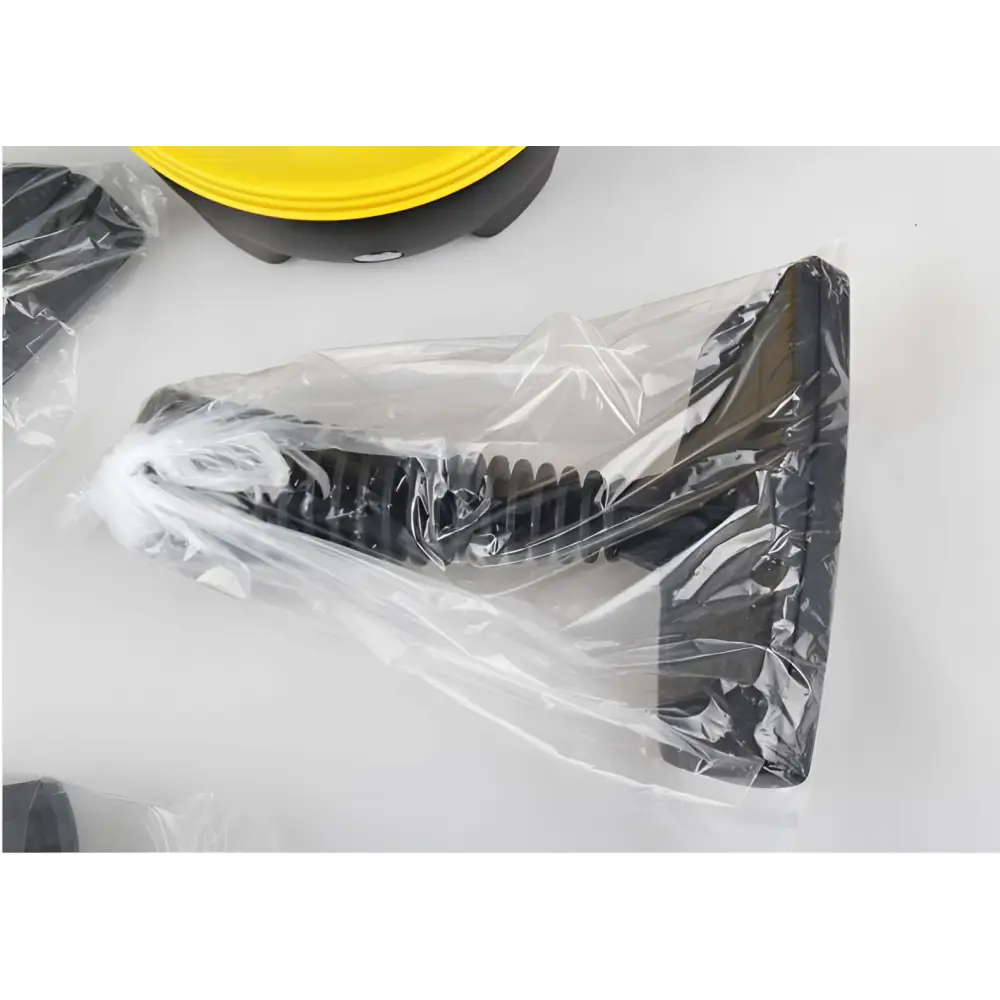 Black plastic foot pedal with coiled spring in clear packaging for yellow and black handheld steam cleaner with flexible nozzle
