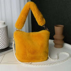 Vibrant yellow checkerboard plush bucket bag with plush faux fur handle and elegant pearl chain design strap