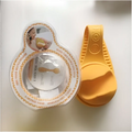 Bright yellow silicone baby bottle holder with curved ergonomic design and textured grip for yellow hands free use