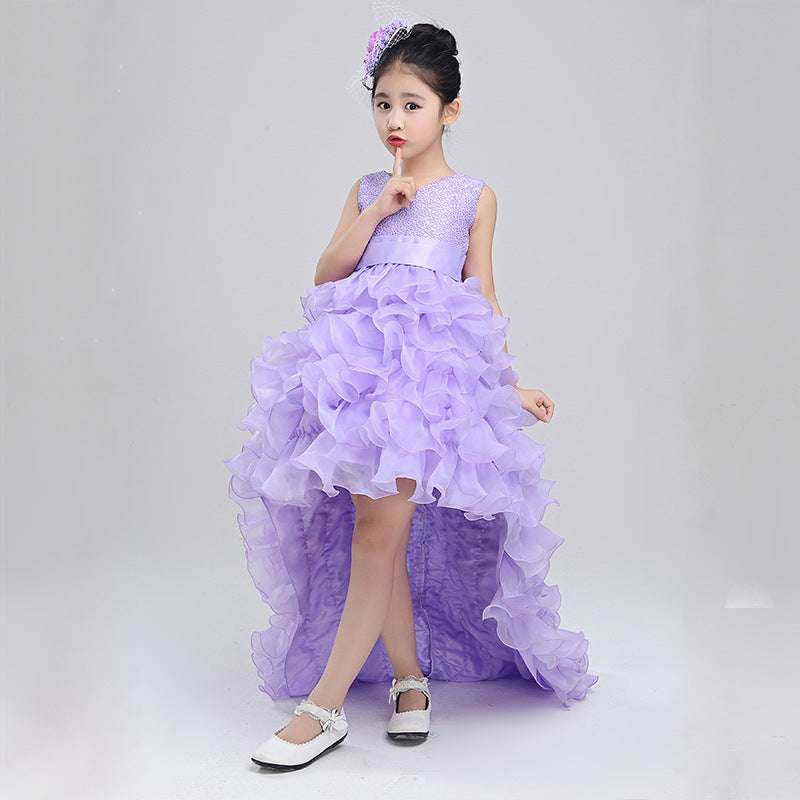 A young girl in a lavender high-low ruffled wedding dress with a sparkling bodice and matching floral headpiece suitable for a flower girl in a bridal party.