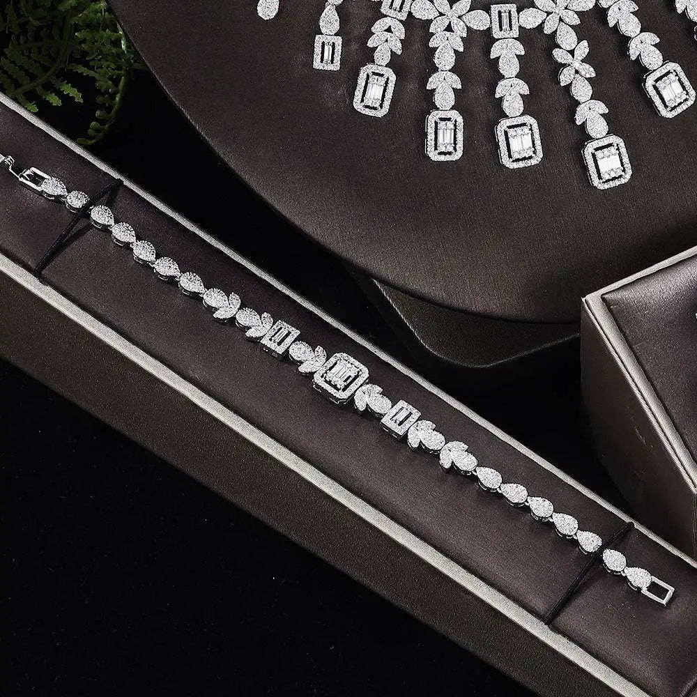 A sparkling zircon necklace with floral and rectangular design displayed on black velvet bust from earrings bracelet ring set