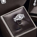 A sparkling silver ring with a central emerald-cut diamond in a zircon earrings bracelet ring set displayed in a black box