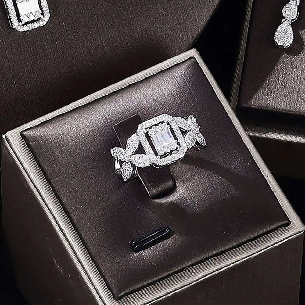 A sparkling silver ring with a central emerald-cut diamond in a zircon earrings bracelet ring set displayed in a black box